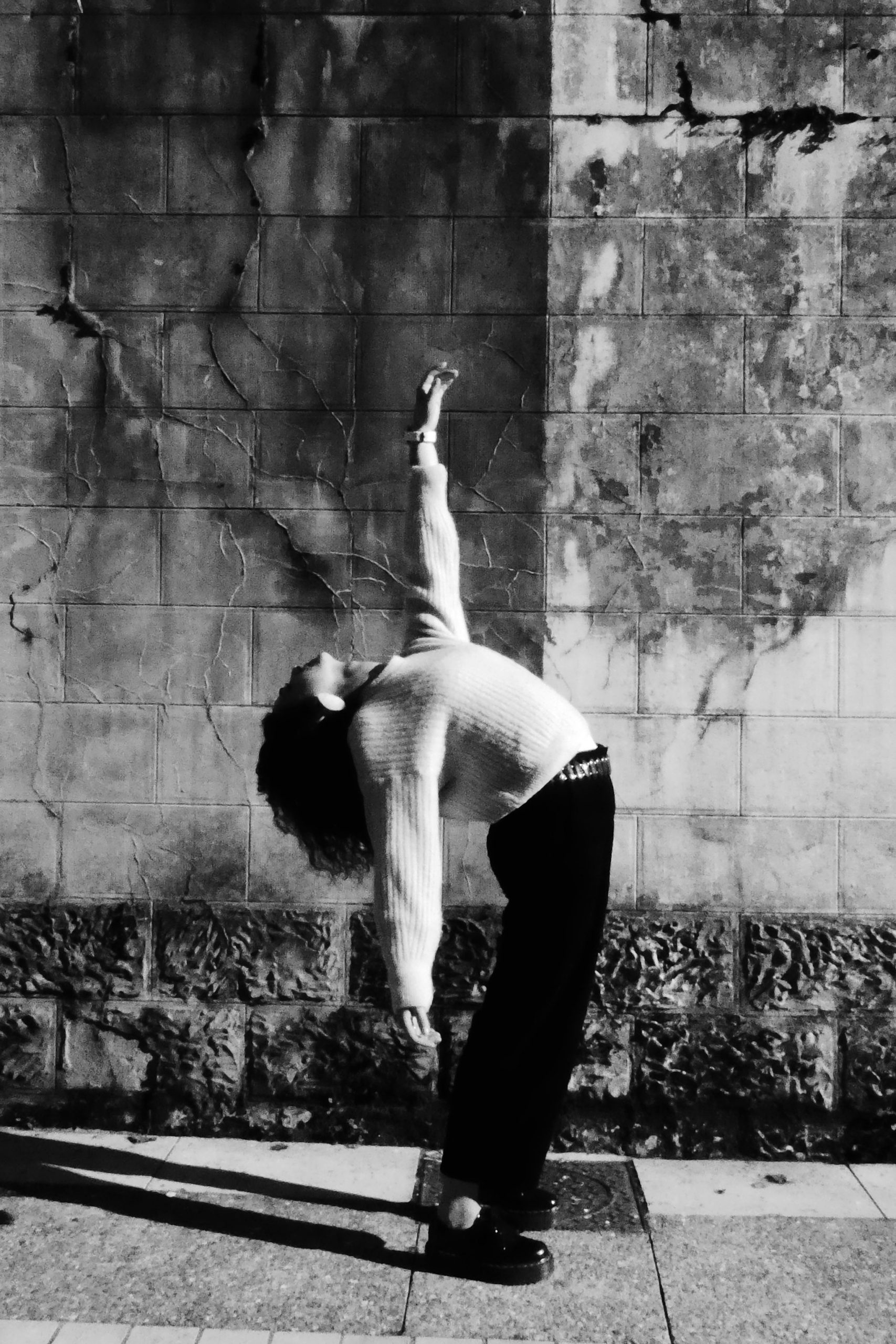 photo en noir et blanc, une danseuse réalise un cambré devant un mur contrasté 
